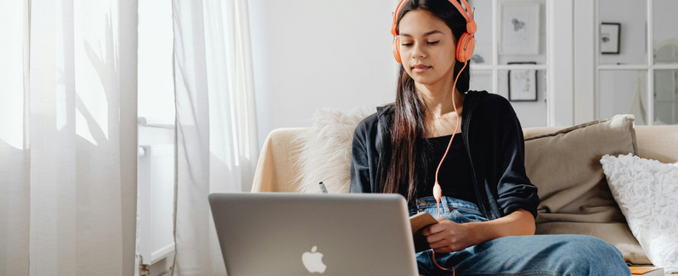 Das Bild von Karolia Grabowska zeigt ein junges Mädchen mit Kopfhörern beim e-Learning.